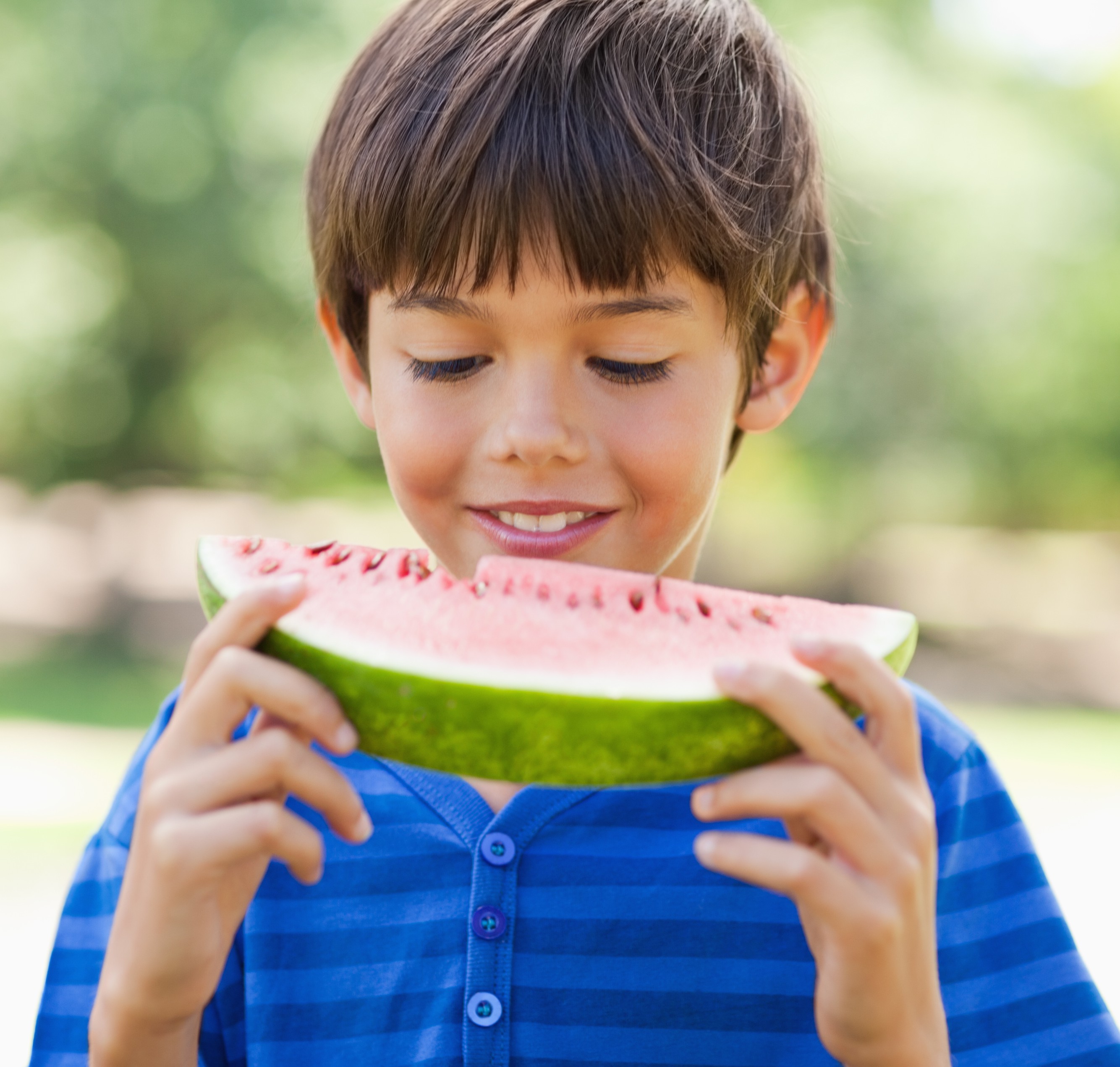 A boy looking at his slice of watermelon
